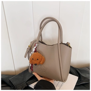 Détail du cabas en cuir taupe grainé avec logo embossé et charm ours en peluche