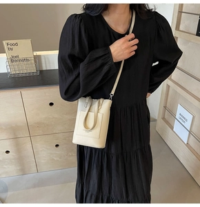 Detailed shot of cream-white pebble leather phone bag with shoulder strap and top handle