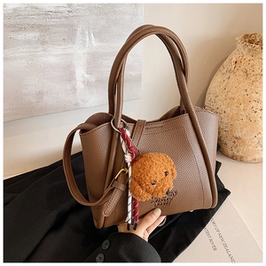 Détail du sac à main en cuir marron avec breloque ours en peluche et cordon tissé élégant