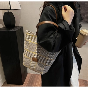 Dettaglio della borsa tote retrò a quadri con tracolla in pelle marrone e toppa logo