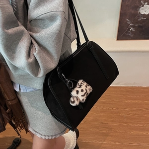 Détail du sac cabas noir à texture mate avec un charmant pendentif en peluche léopard