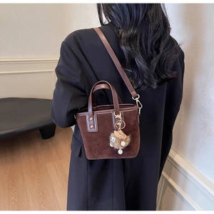 Détail d'un sac cabas vintage en daim marron foncé avec charm en peluche et sangle