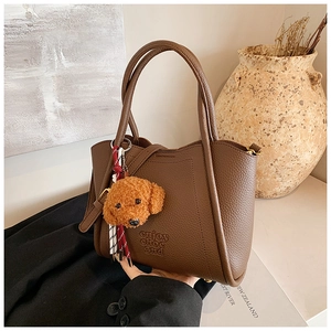 Détail du sac seau marron vintage avec texture litchi et charmant pendentif ours