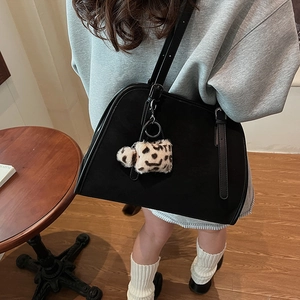 Détail d'un sac cabas en daim noir avec un pendentif décoratif en peluche léopard
