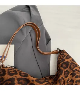 Detail of leopard print tote bag showing slim brown leather straps and smooth zipper closure