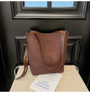Detail view of deep brown suede tote bag with adjustable smooth leather shoulder strap