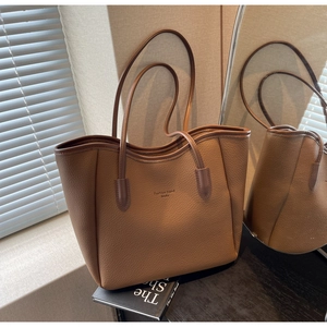 Detailed close-up of brown tote bag showing lychee leather texture under natural light shadows