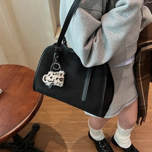 Détail du sac cabas en daim noir avec pompon léopard et finitions métalliques argentées