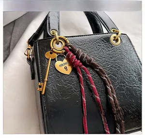 Detail of glossy black embossed leather handbag with gold heart lock and braided key charms