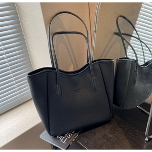 Detail of black pebbled leather tote bag with wavy top edge and Fashion Trend branding