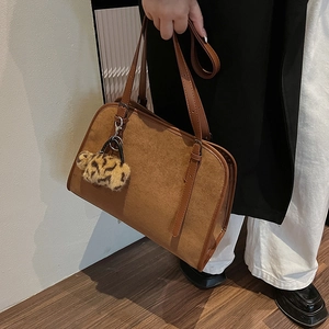 Gros plan sur un sac cabas en daim marron avec garniture en cuir et pompon léopard