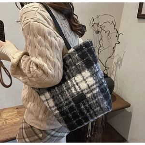 Detail of black and white checkered tote bag featuring plush fabric and leather straps