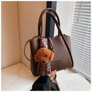 Détail d'un sac cabas marron foncé avec texte gaufré, breloque et bandoulière