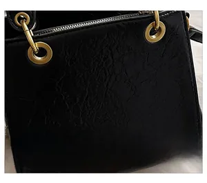 Detail shot of vintage wrinkled leather texture and bronze ring hardware on black bag