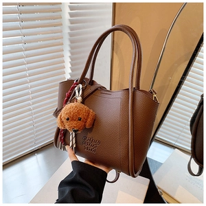 Détail du sac seau en cuir marron avec lettrage embossé et charmant pendentif d'ours