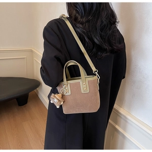 Sac seau en daim marron avec bandoulières vert olive porté à l'épaule de façon élégante