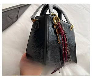 Detail of black wrinkled leather bag with gold hardware and a vintage key pendant