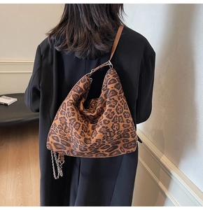 Detail of leopard print hobo bag with leather strap and silver chain on model