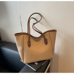 Detail of beige pebble leather tote bag with brown handles on a fashion magazine