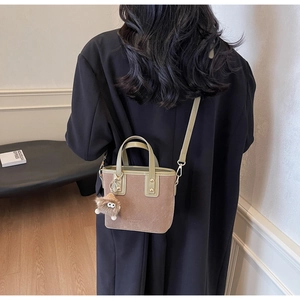 Détail du sac cabas en daim avec charme monstre et poignées en cuir vert olive