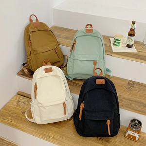 Student backpacks in four colors displayed on wooden steps with minimalist design