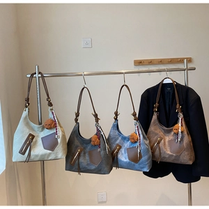 Detail view of four vintage-style shoulder bags in cream, grey, blue, and brown shades