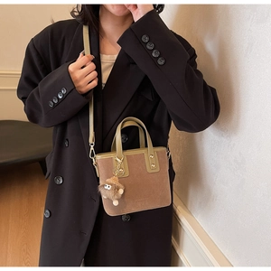 Sac seau en daim marron avec poignée verte et breloque peluche sur un mannequin