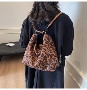 Detail of leopard print tote bag with brown leather straps shown on person in a room