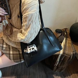 Sac fourre-tout noir rétro avec détail charm en peluche vache dans un décor d'automne