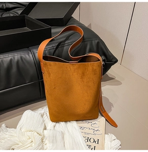 Minimalist bright orange faux suede bucket bag shown with elegant aesthetic props