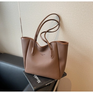 Detail of dark brown lychee leather tote bag with Fashion trend Books logo lettering