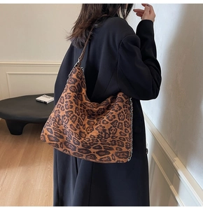 Detail of large leopard print tote bag with metal chain strap worn by a model