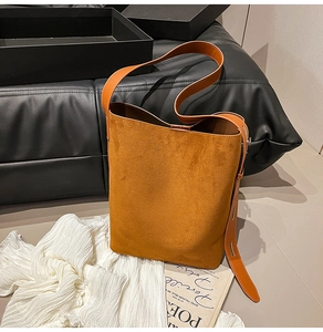 Detail of suede bucket bag with adjustable smooth leather strap on artistic background