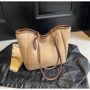 Detail of beige tote bag with litchi leather texture and brown contrast straps