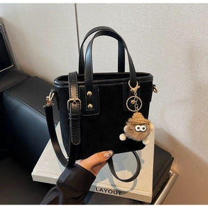 Détail du sac cabas en daim noir avec anses en cuir et breloque en peluche marron