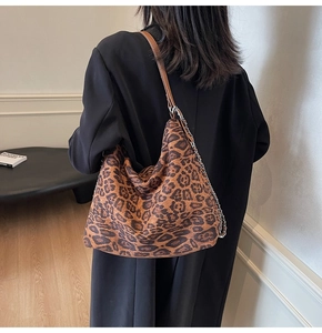 Detail of leopard print tote bag with brown leather strap and silver chain on model