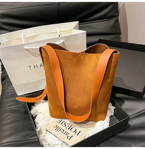 Detail of caramel suede bucket bag showing soft texture and smooth leather shoulder strap