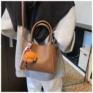 Sac fourre-tout en cuir marron avec breloque nounours porté en bandoulière