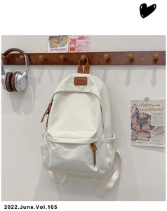 Detail of minimalist off-white canvas backpack with leather logo and front zipper pocket