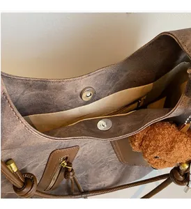 Detail of vintage brown tote bag showing golden magnetic clasp and washed canvas texture