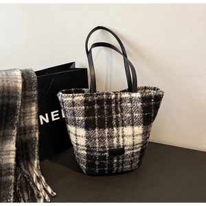Dettaglio della borsa tote in lana a quadri bianchi e neri con manici in pelle e texture
