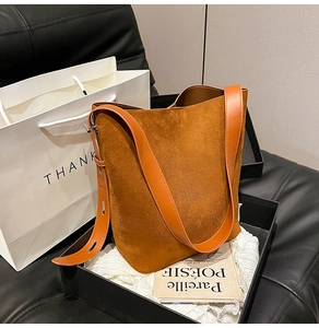 Detailed close-up of caramel suede tote bag with adjustable leather strap in a gift box
