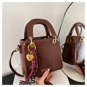 Brown textured leather handbag with gold heart charm and mirror reflection detail