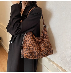 Detail showing the leopard print pattern and faux leather metal chain strap of the hobo bag