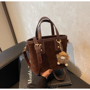 Détail d'un sac cabas marron foncé avec empiècements en daim et un joli pendentif peluche