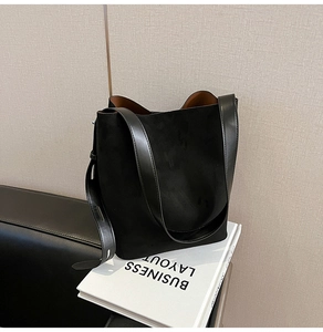 Detail of minimalist black faux suede tote bag with contrast brown lining and leather strap