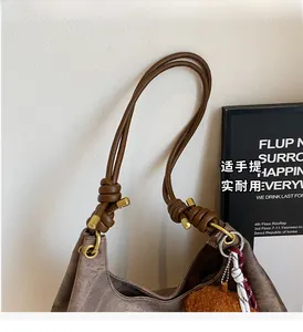 Close-up of brown canvas tote bag with brown leather knotted handle and plush charm