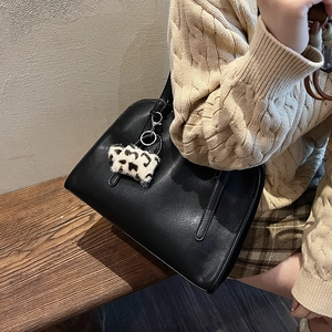Détail d'un sac cabas vintage en cuir noir avec un charm en peluche léopard pour l'hiver
