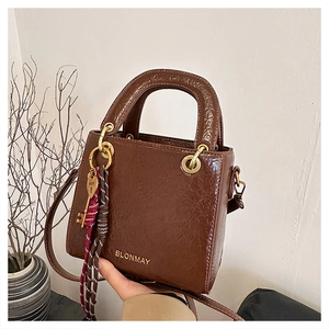 Close-up of brown vintage leather handbag with gold logo and checkered silk scarf