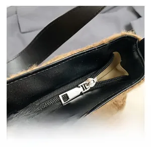Macro detail of brown wool-like fabric with black leather trim and silver zipper closure